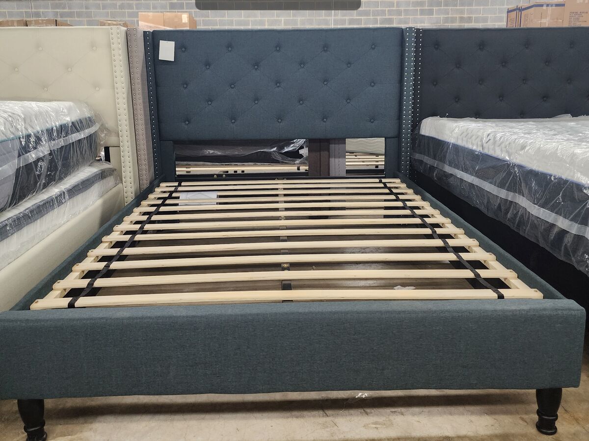 An upholstered platform bed frame in teal.