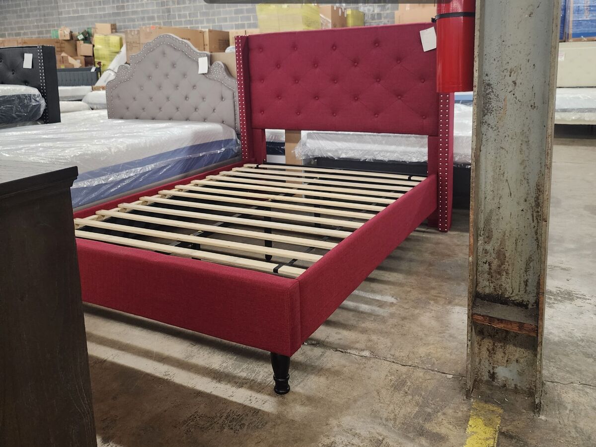 An upholstered platform bed frame in burgundy.
