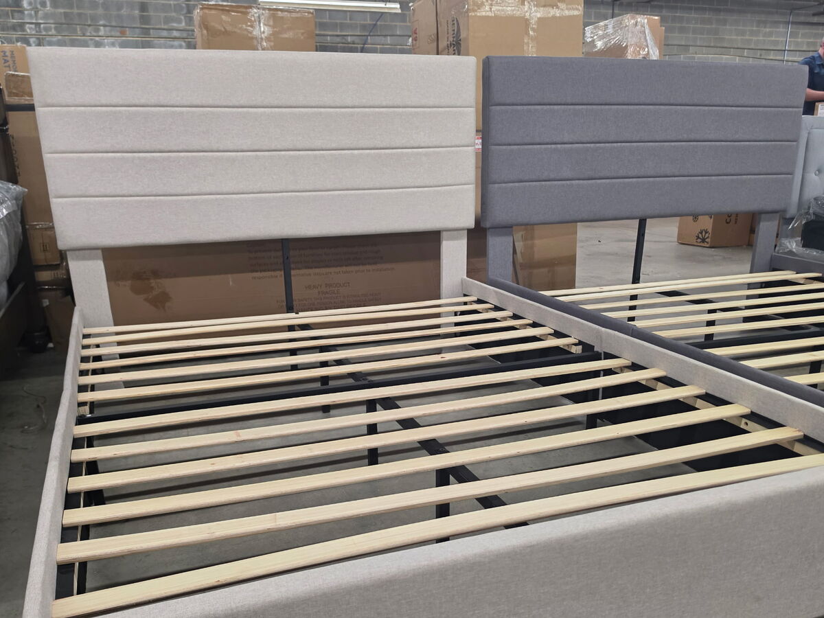 An upholstered platform bed frame in cream and grey.