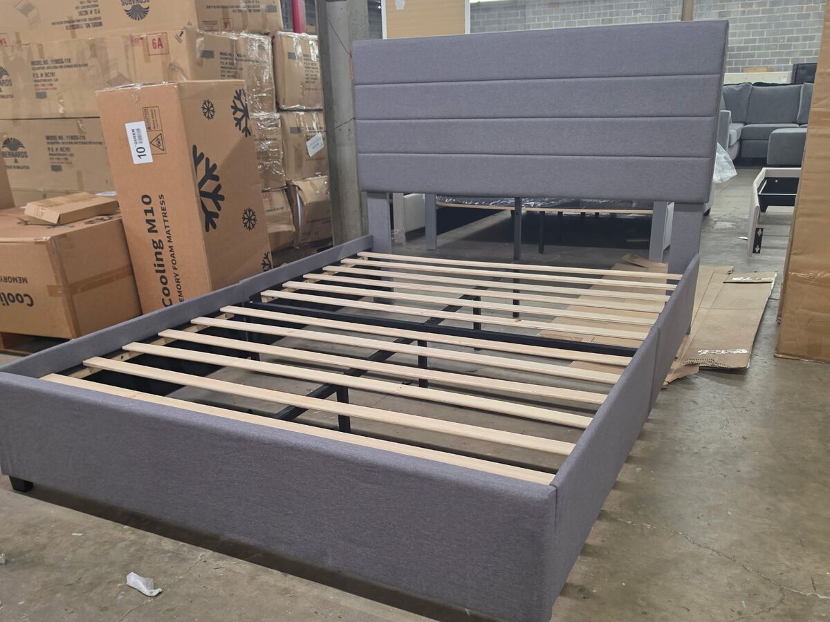An upholstered platform bed frame in light grey.