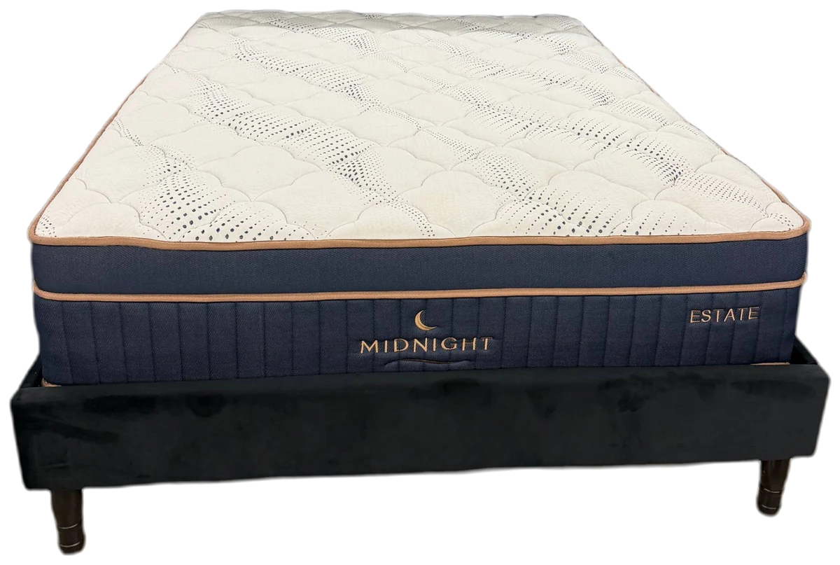 The Midnight Estate mattress on its base, cut out: a cream quilted top over a navy border with gold piping.