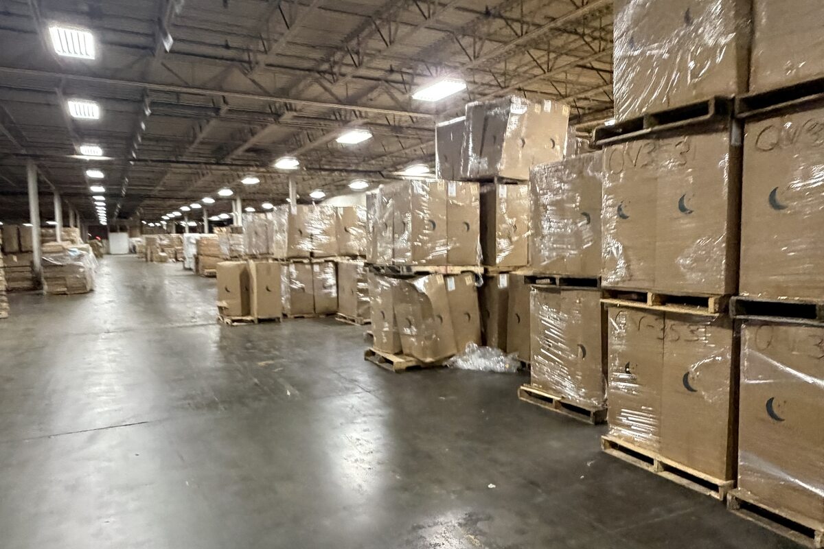 An aisle in the distribution warehouse with wrapped pallets stacked two high running away into the distance.